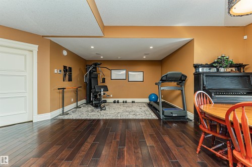This spacious room features rich hardwood flooring, recessed lighting, and warm-toned walls in the basement. - 3048 Watson Landing, Edmonton, AB - Indoor Photo Showing Gym Room