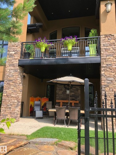 Exterior featuring stone accents, a private upper balcony with black railings, and a ground-level patio - 3048 Watson Landing, Edmonton, AB - Outdoor With Balcony