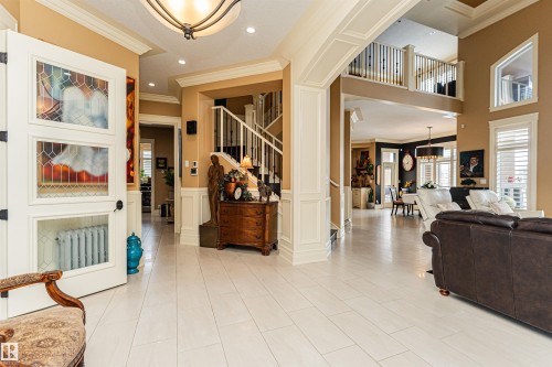 This property features a grand entrance with light-colored flooring and a white staircase with dark railings - 3048 Watson Landing, Edmonton, AB - Indoor Photo Showing Other Room