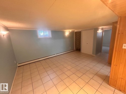 Spacious room featuring light blue walls, ceramic tile flooring, and a small window - 11242 56 Street, Edmonton, AB - Indoor Photo Showing Other Room