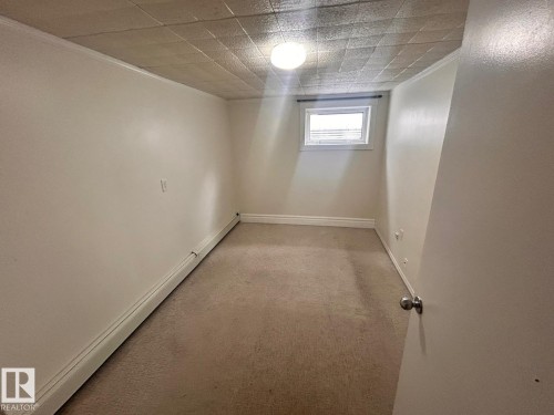 Carpeted room featuring a single window with blinds, baseboard heating, a flush-mount ceiling light, and a textured ceiling - 11242 56 Street, Edmonton, AB - Indoor Photo Showing Other Room