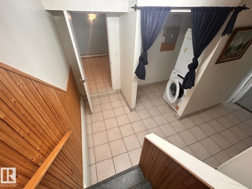 Tiled flooring throughout the landing area, featuring a stacked washer and dryer unit - 11242 56 Street, Edmonton, AB - Indoor Photo Showing Other Room