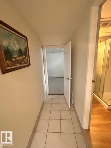 Hallway featuring tile flooring, neutral wall tones, and a doorway opening to a room with carpet flooring - 11242 56 Street, Edmonton, AB - Indoor Photo Showing Other Room