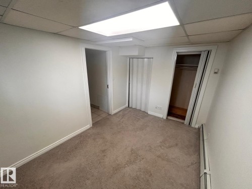 Carpeted room featuring white walls, a drop ceiling with recessed lighting, and a closet with a built-in hanging rod - 11242 56 Street, Edmonton, AB - Indoor Photo Showing Other Room