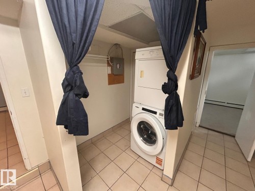 Dedicated laundry area featuring a stacked washer and dryer unit - 11242 56 Street, Edmonton, AB - Indoor Photo Showing Laundry Room