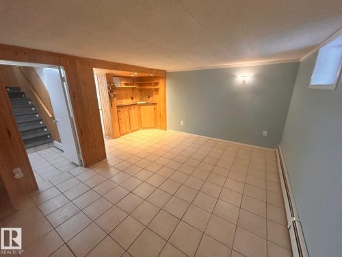 Spacious room featuring tile flooring, light blue walls, and wood-paneled accents - 11242 56 Street, Edmonton, AB - Indoor Photo Showing Other Room