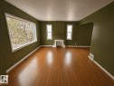 Spacious room featuring wood-finish flooring, a decorative fireplace with a mantel, and an arched doorway - 11242 56 Street, Edmonton, AB  - Indoor 