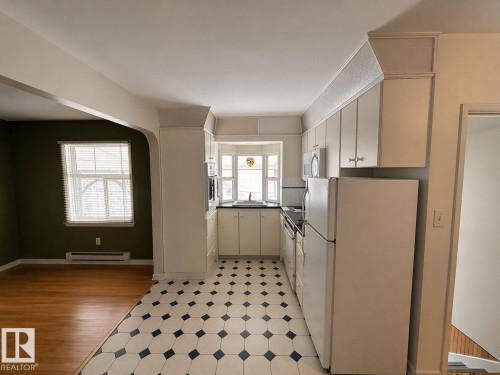 Galley kitchen featuring white cabinetry, black and white geometric floor tiling, and a bay window - 11242 56 Street, Edmonton, AB - Indoor