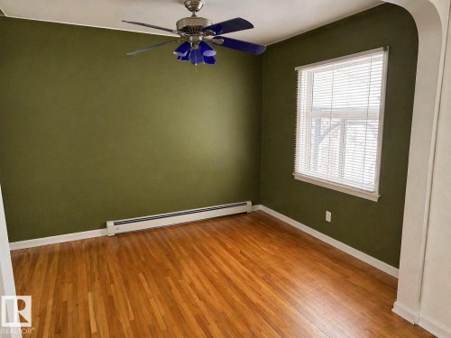 Hardwood flooring complements olive green walls - 11242 56 Street, Edmonton, AB - Indoor Photo Showing Other Room