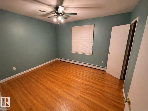Hardwood flooring across a spacious room featuring a ceiling fan with integrated lighting - 11242 56 Street, Edmonton, AB - Indoor Photo Showing Other Room