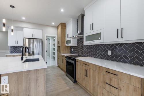 Modern kitchen featuring two-tone cabinetry with white upper and wood-finish lower cabinets - 917 Elderberry Landing, Edmonton, AB - Indoor Photo Showing Kitchen With Upgraded Kitchen