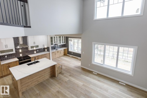 Open-concept living area featuring high ceilings and light wood-finish flooring - 917 Elderberry Landing, Edmonton, AB - Indoor Photo Showing Kitchen