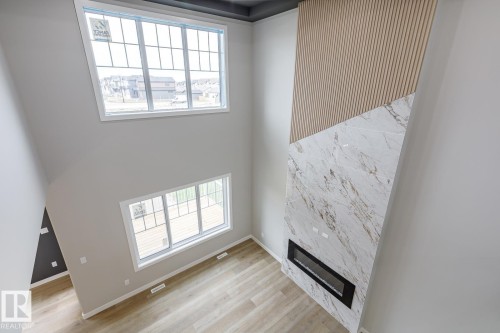 High ceilings featuring a two-story accent wall with wood paneling and a large-format tile surround - 917 Elderberry Landing, Edmonton, AB - Indoor Photo Showing Other Room