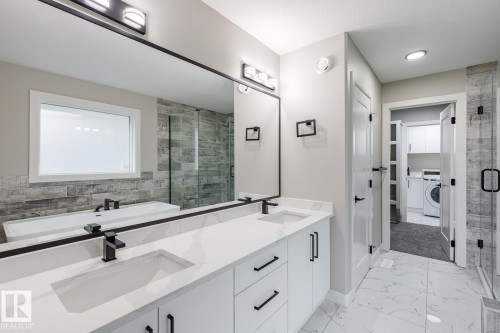 Bathroom featuring a dual vanity with white cabinetry, integrated sinks, and black hardware - 917 Elderberry Landing, Edmonton, AB - Indoor Photo Showing Bathroom