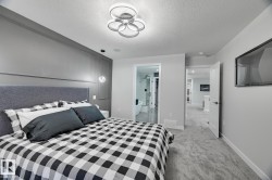 Carpeted bedroom featuring a contemporary ceiling fixture, a paneled accent wall, and a mounted flat-screen television - 