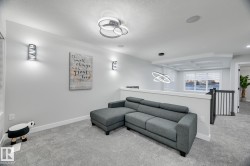 Carpeted upper-level landing featuring modern recessed lighting, contemporary wall sconces, and sleek ceiling light fixtures - 
