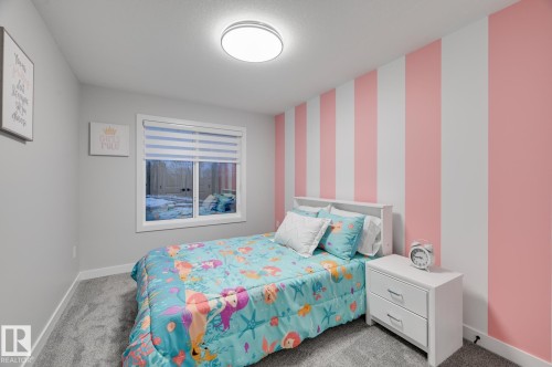 Bedroom featuring a full-size window with blinds, a prominent striped accent wall, light gray walls, plush carpeting, and a flush-mount ceiling light - 1774 Crossbill Loop, Edmonton, AB - Indoor Photo Showing Bedroom
