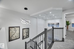 Upper-level landing featuring a contemporary chandelier and dark wood newel posts with black metal balusters - 