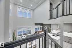 Multi-level interior featuring a contemporary staircase with dark wood-finish railing and black spindles - 