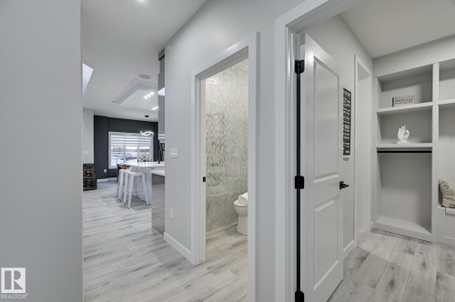 Entryway featuring light wood-finish flooring, built-in shelving, and white paneled doors with matte black hardware - 1774 Crossbill Loop, Edmonton, AB - Indoor Photo Showing Other Room