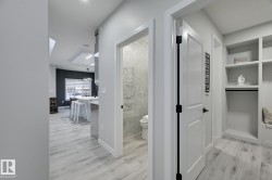 Entryway featuring light wood-finish flooring, built-in shelving, and white paneled doors with matte black hardware - 