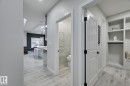 Entryway featuring light wood-finish flooring, built-in shelving, and white paneled doors with matte black hardware - 1774 Crossbill Loop, Edmonton, AB  - Indoor Photo Showing Other Room 