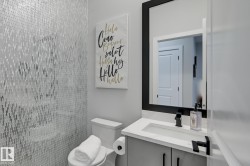 Powder room featuring a full-height mosaic tile accent wall, a vanity with a white countertop and integrated sink, matte black faucet, and a large mirror with a black frame - 