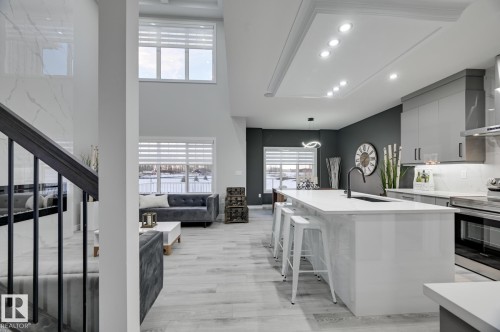 Open-concept living space featuring a gourmet kitchen with a large white island, integrated appliances, and light wood-finish flooring - 1774 Crossbill Loop, Edmonton, AB - Indoor Photo Showing Kitchen With Upgraded Kitchen