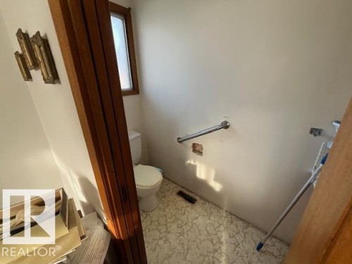A bathroom with a toilet, a window with wood trim, and a grab bar on the wall - 11003 144 Street, Edmonton, AB - Indoor Photo Showing Bathroom