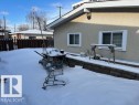 The property features a stucco exterior, white-framed windows, and a multi-tiered yard area with a retaining wall - 11003 144 Street, Edmonton, AB  - Outdoor 