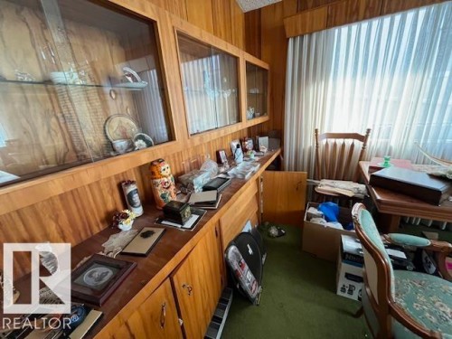 This room features wood paneling, wood cabinetry with glass display fronts, and a large window with vertical blinds - 11003 144 Street, Edmonton, AB - Indoor