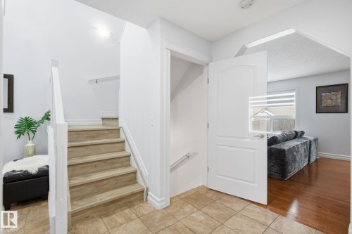 Foyer featuring ceramic tile flooring, wood-finish stairs with white risers and handrails, and an arched doorway - 3016 24 Ave, Edmonton, AB - Indoor Photo Showing Other Room