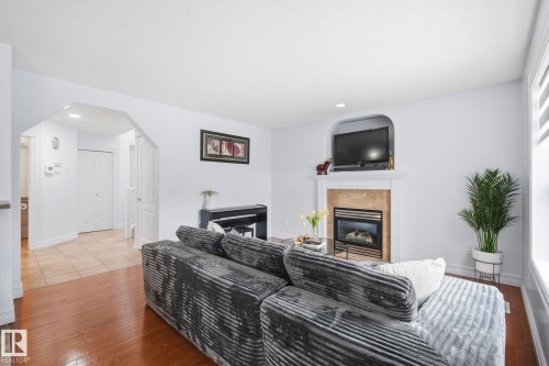 Living area featuring a fireplace with a stone surround and a white mantel - 3016 24 Ave, Edmonton, AB - Indoor Photo Showing Living Room With Fireplace