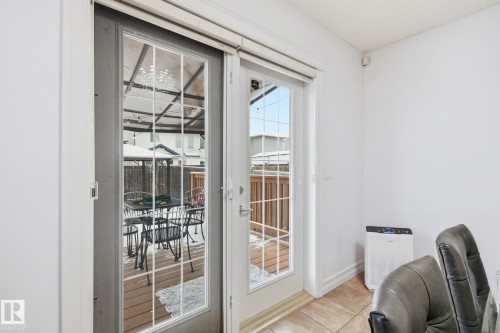 Sliding patio door with grid-patterned glass panels, accompanied by a single French door, opening onto a backyard wood deck with a privacy fence - 3016 24 Ave, Edmonton, AB - Indoor Photo Showing Other Room