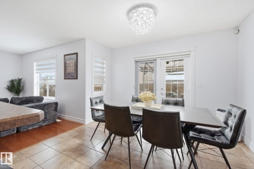 Dining area featuring tile flooring, a contemporary chandelier, and patio door access to the exterior - 3016 24 Ave, Edmonton, AB - Indoor Photo Showing Dining Room