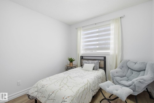 Bright room featuring wood-finish flooring, white painted walls, and a window with blinds and drapes - 3016 24 Ave, Edmonton, AB - Indoor Photo Showing Bedroom
