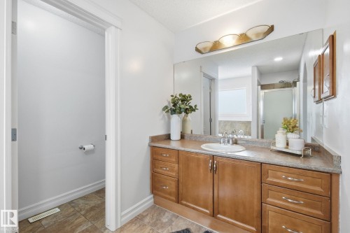 Spacious vanity with light wood-finish cabinetry, a single basin sink, and a large wall-mounted mirror - 3016 24 Ave, Edmonton, AB - Indoor Photo Showing Bathroom