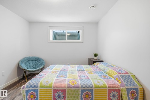 Bedroom featuring a window with a white frame, wood-finish flooring, and white walls - 3016 24 Ave, Edmonton, AB - Indoor Photo Showing Bedroom