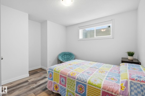 Bedroom featuring wood-finish flooring, white baseboards, a white interior door with a silver handle, a white window frame, and a flush-mount ceiling light - 3016 24 Ave, Edmonton, AB - Indoor Photo Showing Bedroom