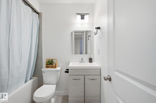 Bathroom featuring a white vanity with integrated sink, chrome faucet, and matte black lighting fixture - 3016 24 Ave, Edmonton, AB - Indoor Photo Showing Bathroom