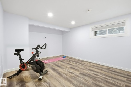 Versatile room featuring wood-finish flooring, recessed lighting, a white trim window, and white painted walls - 3016 24 Ave, Edmonton, AB - Indoor Photo Showing Gym Room