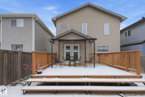 Rear exterior featuring a spacious wood deck with wood railings, a metal gazebo, and white French doors - 3016 24 Ave, Edmonton, AB - Outdoor With Exterior