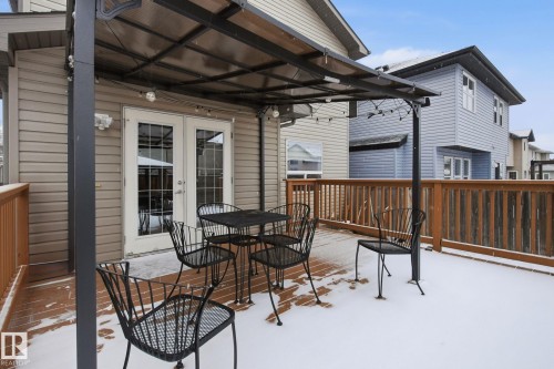 Expansive wood-finish deck with a built-in privacy screen, covered pergola, and double patio doors - 3016 24 Ave, Edmonton, AB - Outdoor With Deck Patio Veranda With Exterior