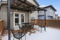Expansive wood-finish deck with a built-in privacy screen, covered pergola, and double patio doors - 