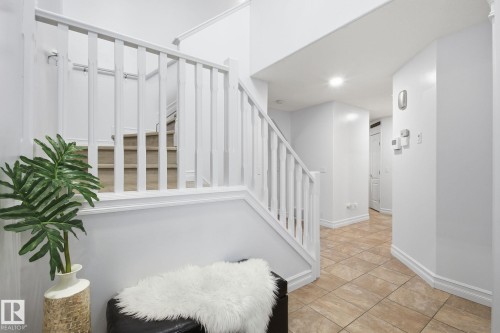 Staircase with white balusters and carpeted treads, complemented by light-toned tile flooring in the entry area - 3016 24 Ave, Edmonton, AB - Indoor