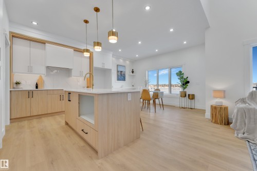 Open-concept kitchen with a light wood-finish island, white countertops, and contemporary pendant lighting - 247 Linden Loop, Leduc, AB - Indoor Photo Showing Kitchen With Upgraded Kitchen
