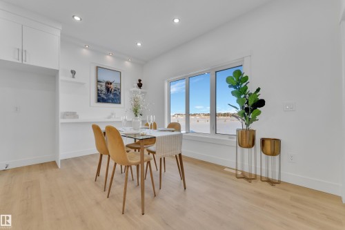 Bright interior space featuring large windows, wood-finish flooring, recessed lighting, white cabinetry, and a wall-mounted shelf system - 247 Linden Loop, Leduc, AB - Indoor Photo Showing Dining Room