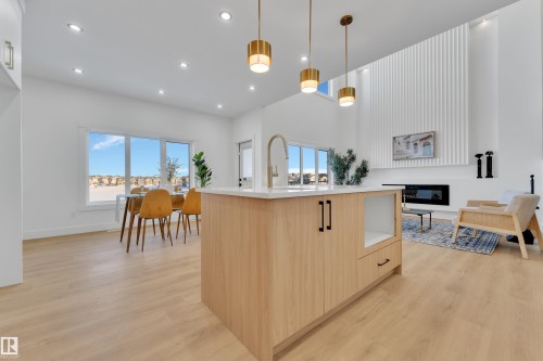 Open-concept living space featuring wood-finish flooring, a kitchen island with integrated storage, and recessed ceiling lighting - 247 Linden Loop, Leduc, AB - Indoor