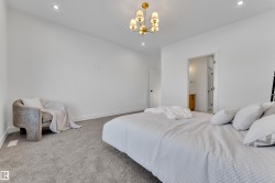 Spacious room featuring neutral carpeting, recessed lighting, and a modern gold-toned chandelier - 