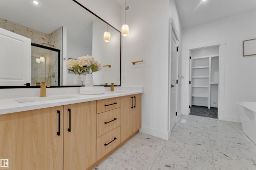 Spacious bathroom featuring a double vanity with light wood-finish cabinetry, white countertops, and gold-finish fixtures - 247 Linden Loop, Leduc, AB - Indoor Photo Showing Other Room